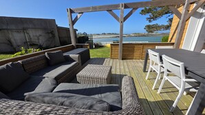 Une terrasse en bois avec un canapé en osier et une table entourée de chaises.