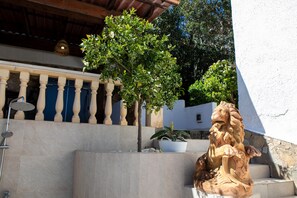 Relax on a serene balcony with a stone bench and decorative lion statue, surrounded by lush greenery and a beautiful view.