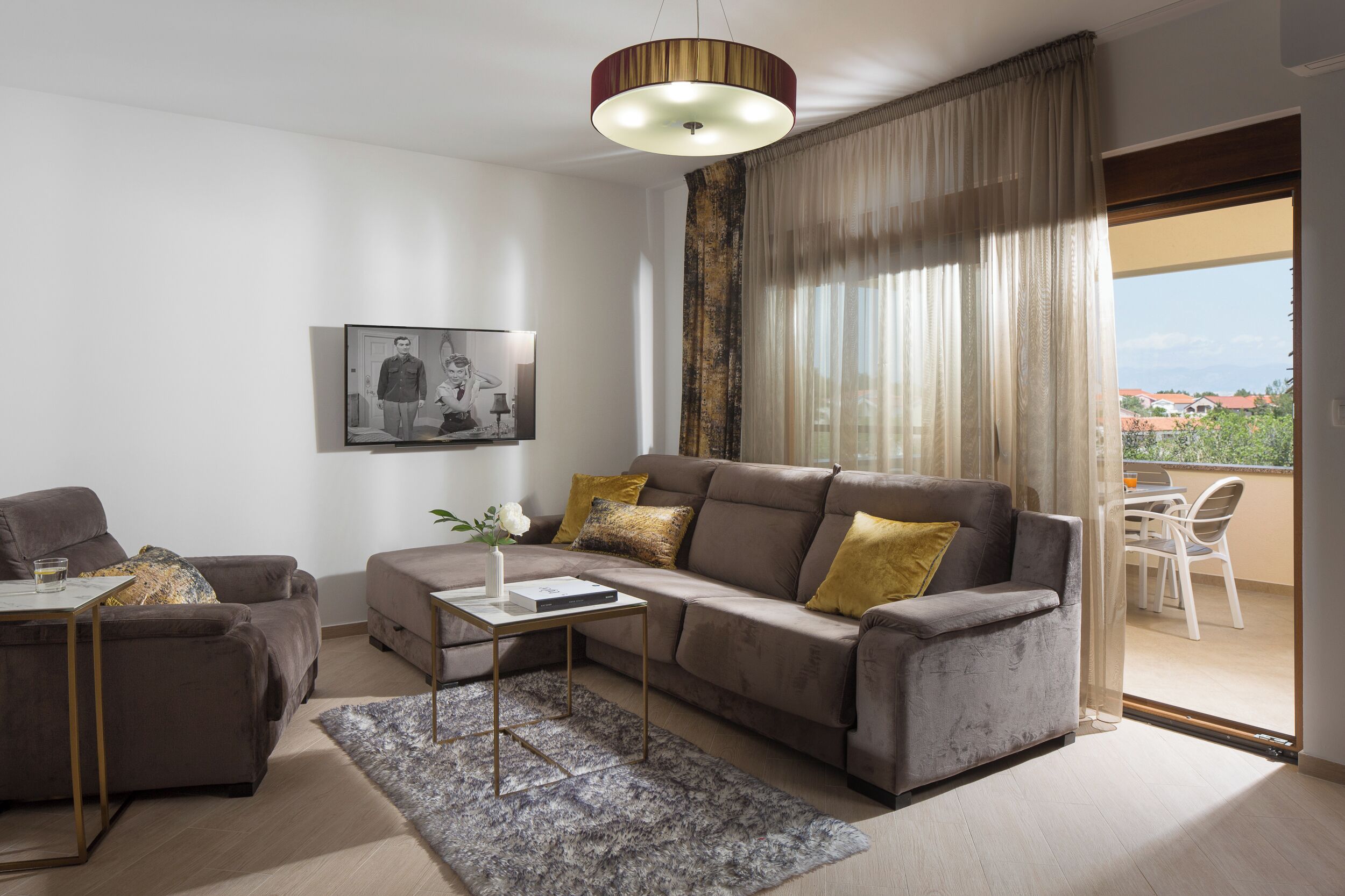 A modern living room with a grey sofa, a coffee table, and a dining area with a table and chairs.