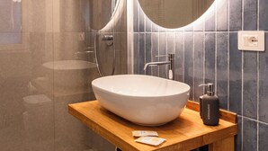 A modern bathroom with a large oval sink, a round mirror, and a handheld showerhead. - VERNAZZA - ANGEINETTA, elegant suite-loft with every comfort (vernazza)