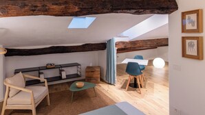 A cozy loft-style room with exposed wooden beams, a skylight, a sofa, a dining table with chairs, and artwork on the walls. - VERNAZZA - ANGEINETTA, elegant suite-loft with every comfort (vernazza)