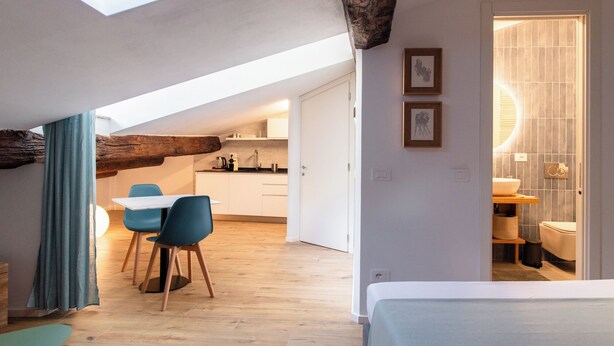 A modern loft bedroom with a skylight, a dining area with blue chairs, and a kitchen in the background. - VERNAZZA - ANGEINETTA, elegant suite-loft with every comfort (vernazza)