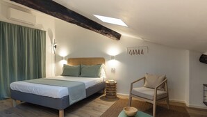 A bedroom with a bed, a chair, a small table, and a wall-mounted light fixture. - VERNAZZA - ANGEINETTA, elegant suite-loft with every comfort (vernazza)