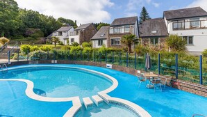 A swimming pool with a curved design, surrounded by a fence and a row of houses. - Pet free Croft Cottage (Truro)