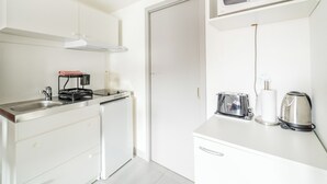 A compact kitchen with a microwave, toaster, kettle, and a coffee machine.
