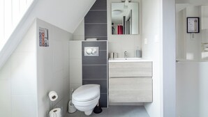A modern bathroom with a toilet, sink, and mirror.