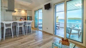 Una cocina moderna con barra, puertas de vidrio correderas que dan a un balcón con vista al mar.
