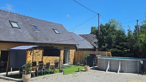 A house with a stone facade, a sloped roof, a swimming pool, and outdoor seating. - Country house with indoor jacuzzi (Couesmes-Vaucé)