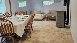 A spacious dining area with a large table set for six, surrounded by wooden chairs. There is a sofa and a television in the background. - Country house with indoor jacuzzi (Couesmes-Vaucé)