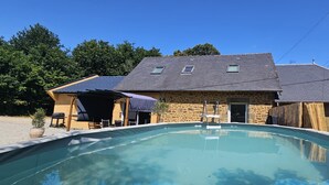 A swimming pool with a stone building in the background. - Country house with indoor jacuzzi (Couesmes-Vaucé)