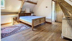 A bedroom with a wooden bed, a nightstand, a dresser, and a patterned rug. - Country house with indoor jacuzzi (Couesmes-Vaucé)