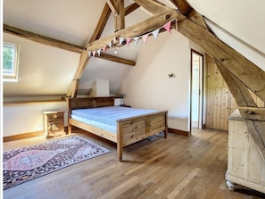 A bedroom with a wooden bed, a nightstand, a dresser, and a patterned rug.