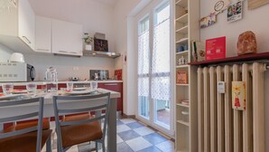 Una cocina moderna con comedor, que presenta piso de cuadros, armarios blancos y un radiador.