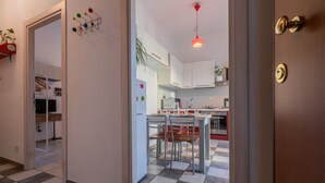 Cocina moderna con piso a cuadros, gabinetes blancos y una lámpara colgante roja.