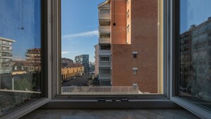 Vista desde una ventana sobre una calle de la ciudad con edificios y cielo despejado.