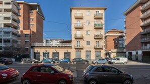 Un edificio de varios pisos con balcones y un estacionamiento con coches.