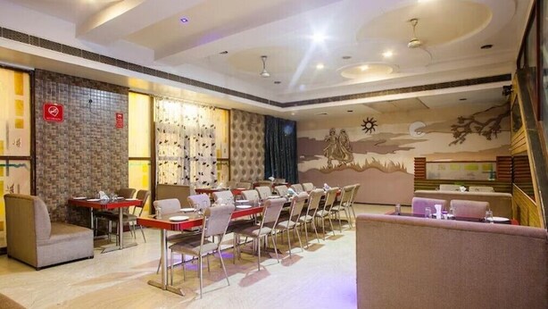 Un hall d’hôtel avec une longue table à manger, plusieurs chaises, un canapé et une fresque murale décorative.