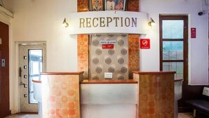 Un espace d’accueil avec une pancarte indiquant « RÉCEPTION », une autre indiquant « DÉFENSE DE FUMER » et un avis indiquant l’heure limite pour quitter la chambre.