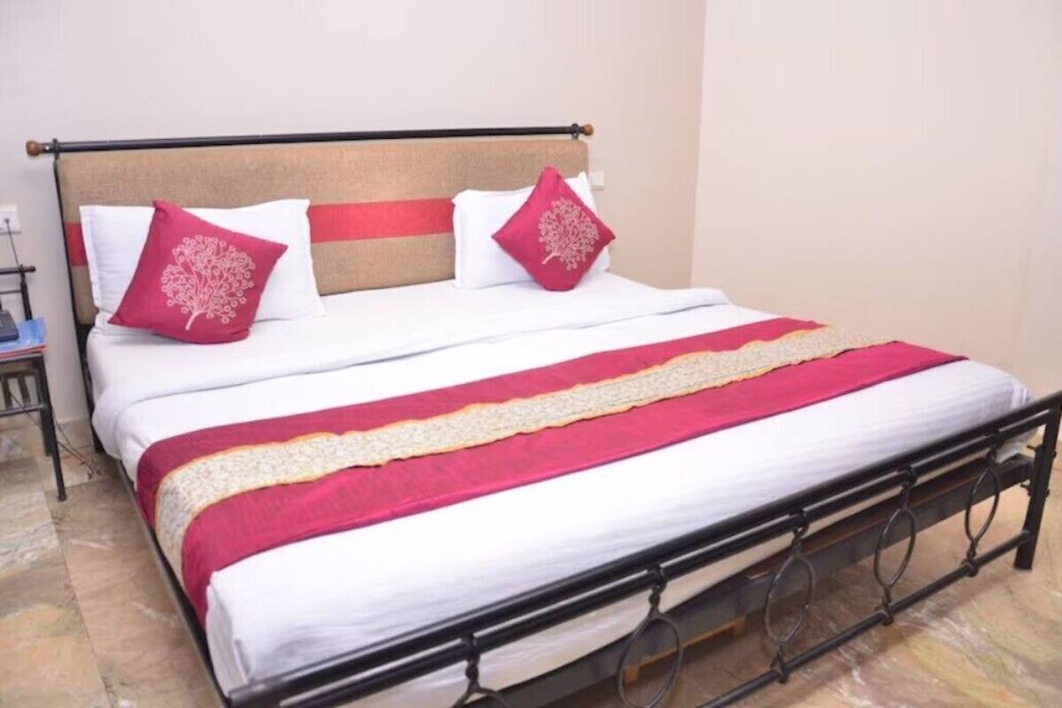 A bed with a wooden headboard, white bedding, and red accents.