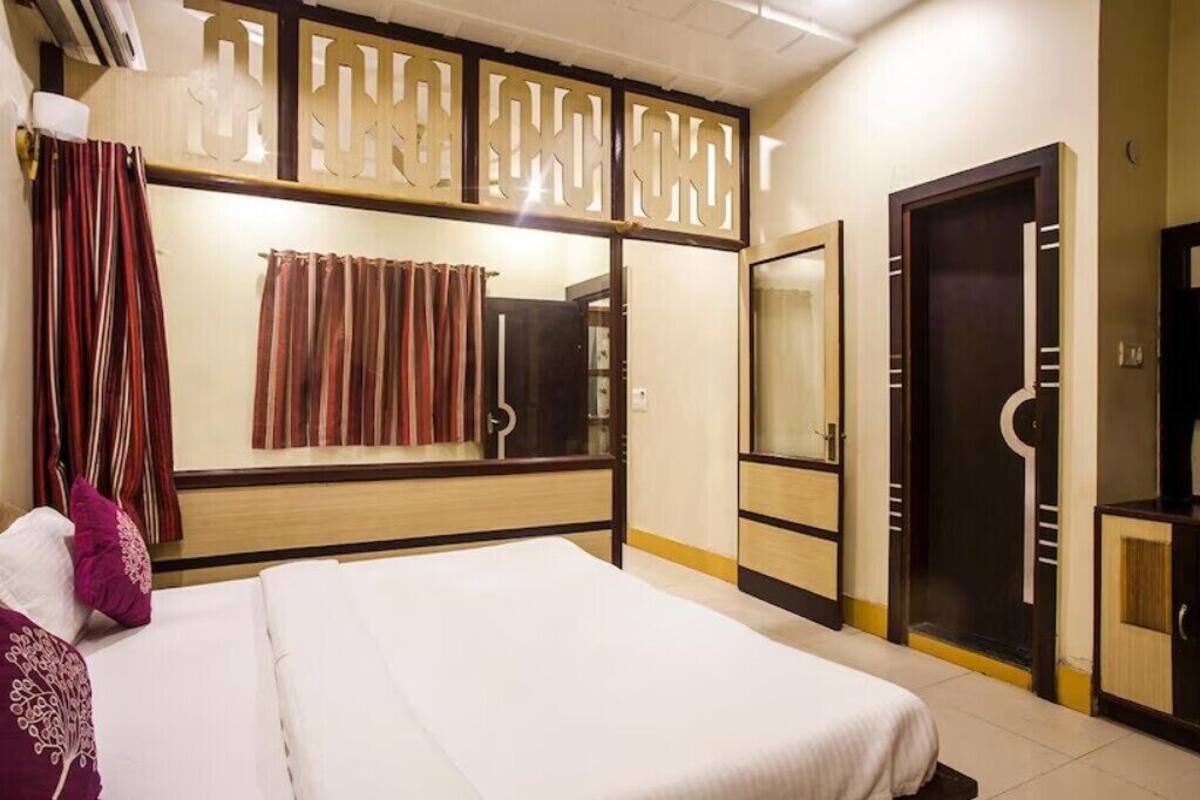 A hotel room with a bed, a mirror, a wardrobe, and a shower area.