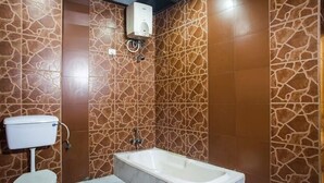 Une salle de bain équipée de toilettes, d’une baignoire et d’un chauffe-eau mural.