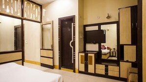 Une chambre d’hôtel comprenant un lit, une armoire, une télévision et un miroir.