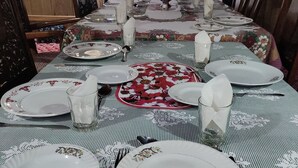 A dining table set for a meal with plates, glasses, and cutlery. - Queens Lake House (Srinagar)