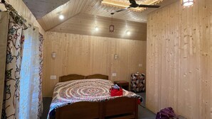 A wooden-paneled room with a bed, a ceiling fan, recessed lighting, and a hanging light fixture. - Queens Lake House (Srinagar)