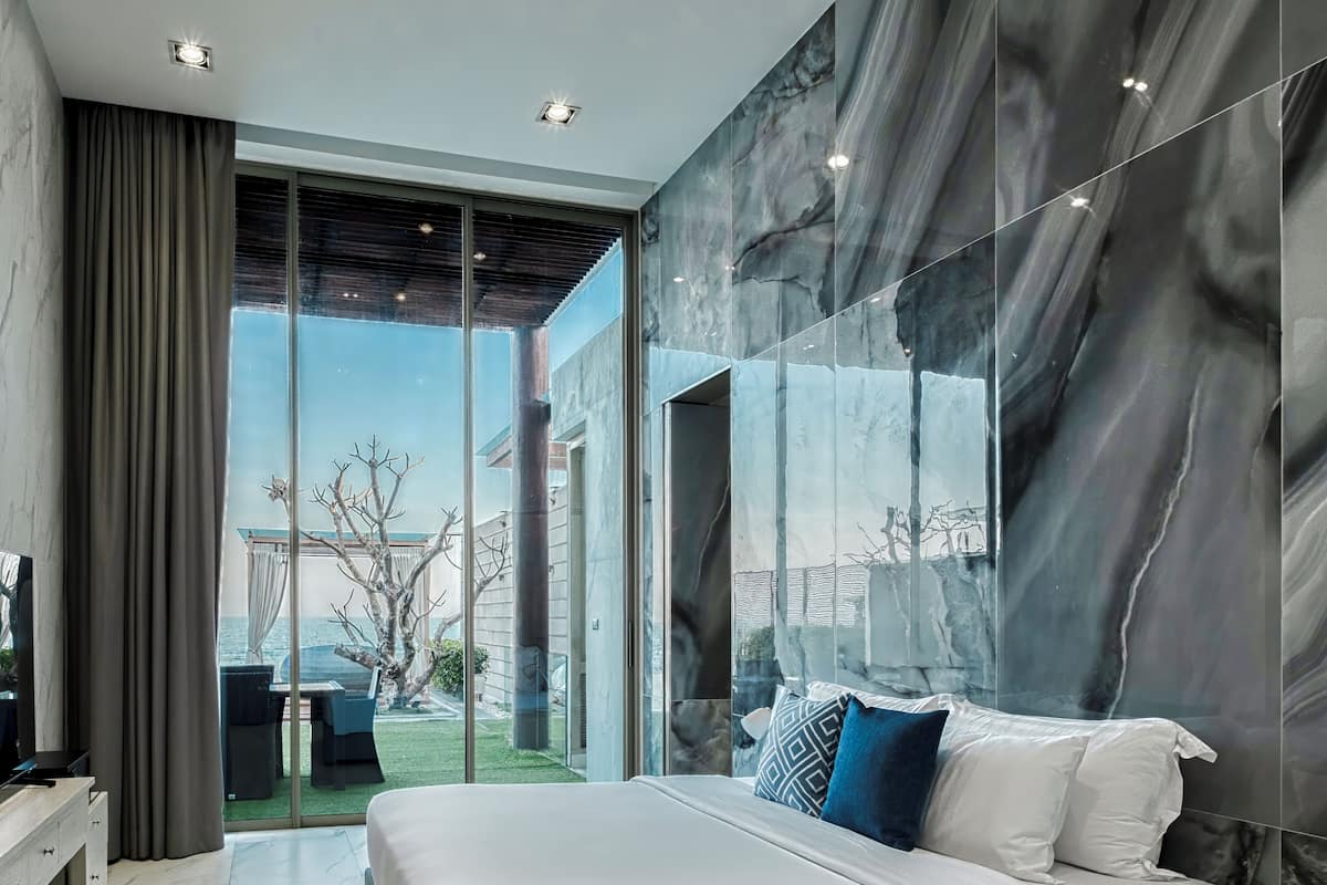 Een moderne slaapkamer met een groot bed, een televisie en een glazen deur naar een buitenruimte.