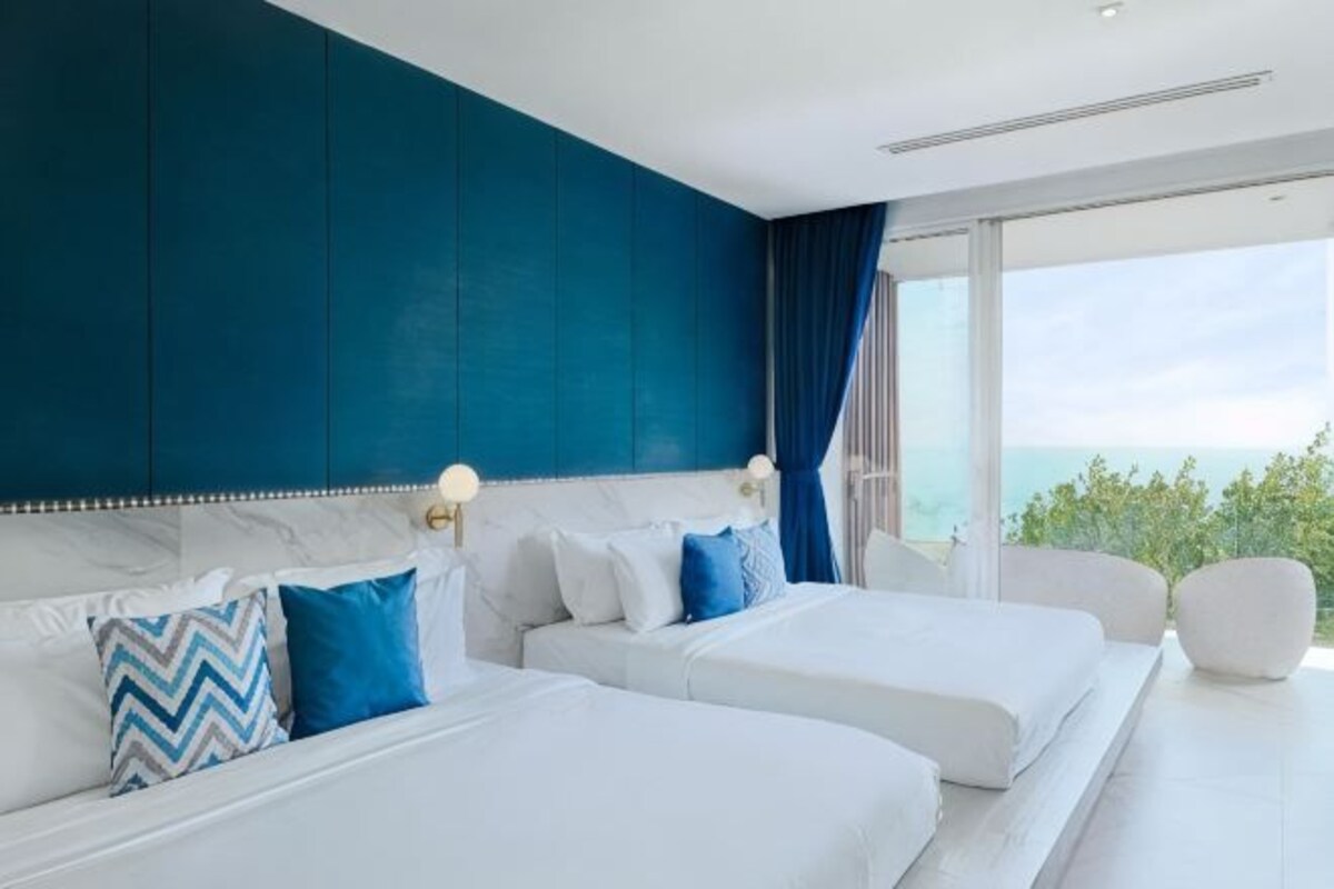 Ett modernt hotellrum med två sängar, ett stort fönster och utsikt över omgivningarna.
