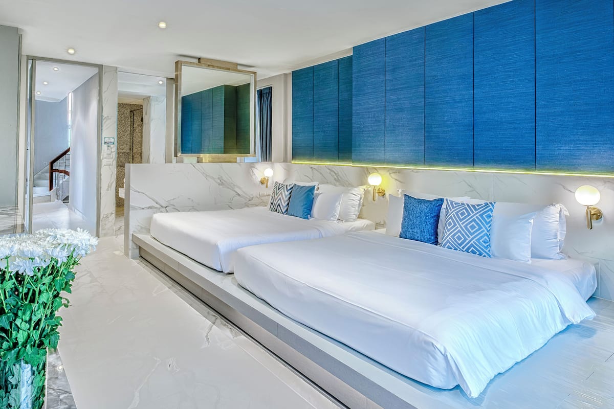 Een moderne hotelkamer met een groot bed, een spiegel en een blauwe accentmuur.