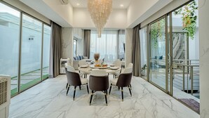 Un comedor moderno con piso de mármol, una lámpara de araña y una mesa dispuesta para cuatro comensales.