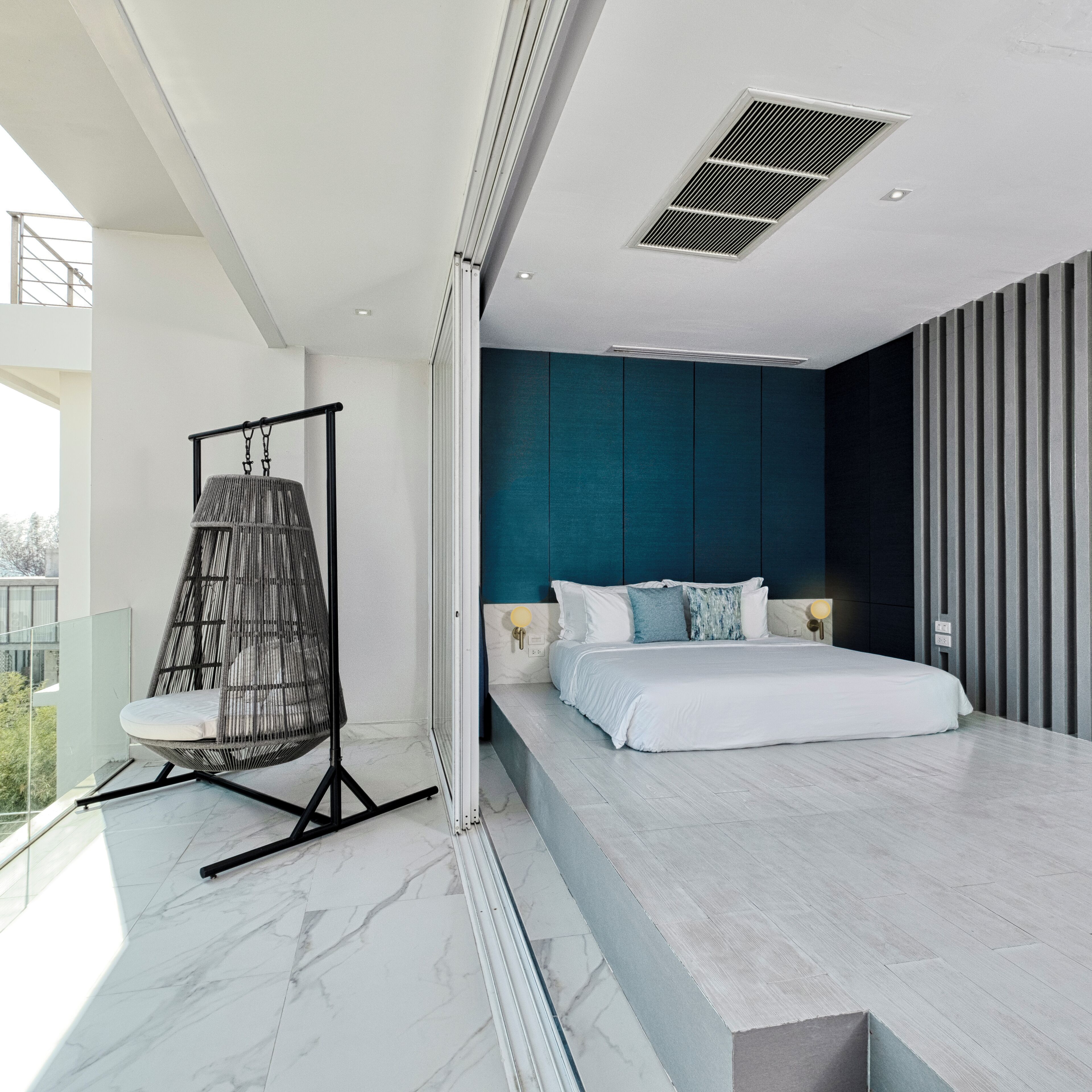 A modern bedroom with a bed, a hanging chair, and a view of the outdoors.