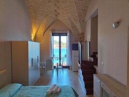 Un dormitorio con cama, escritorio y vista al mar.