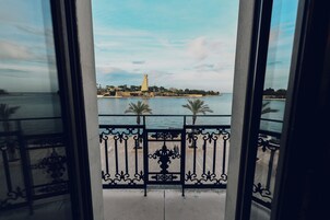 Un balcón con vistas a la costa, incluyendo un faro y palmeras.