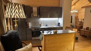 Een gezellige keuken met houten kastjes, een centraal eiland en een eethoek met een stoel en tafel.
