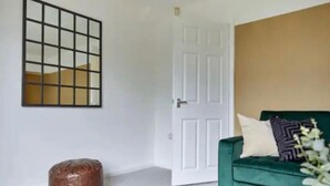 A room with a green sofa, a white door, and a wall-mounted grid pattern.