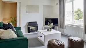 A living room with a green sofa, a white coffee table, a television, and a fireplace.