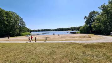 A lakeside park with walking paths, a dock, and dense trees.