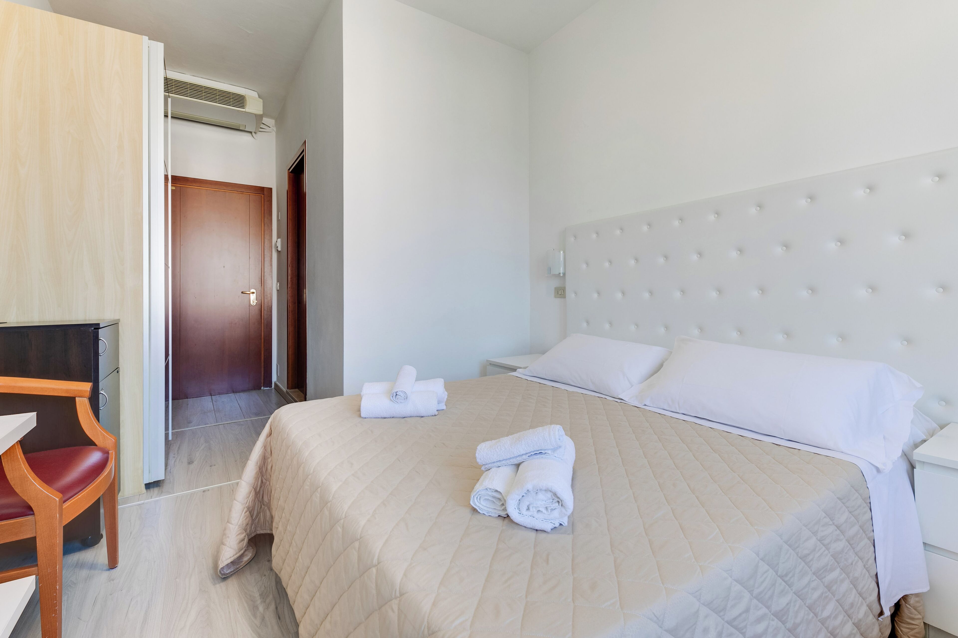 Una habitación de hotel con una cama, un escritorio y una silla.