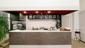 A modern kitchen with a central island, a wine rack above, and a potted plant to the left. - Hotel La Perla (Rimini)