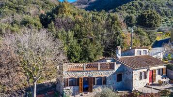 Una casa in pietra con un balcone e vista su un paesaggio montuoso.