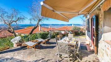 Un patio con tavolo e sedie, un lettino prendisole e vista su edifici dai tetti rossi.