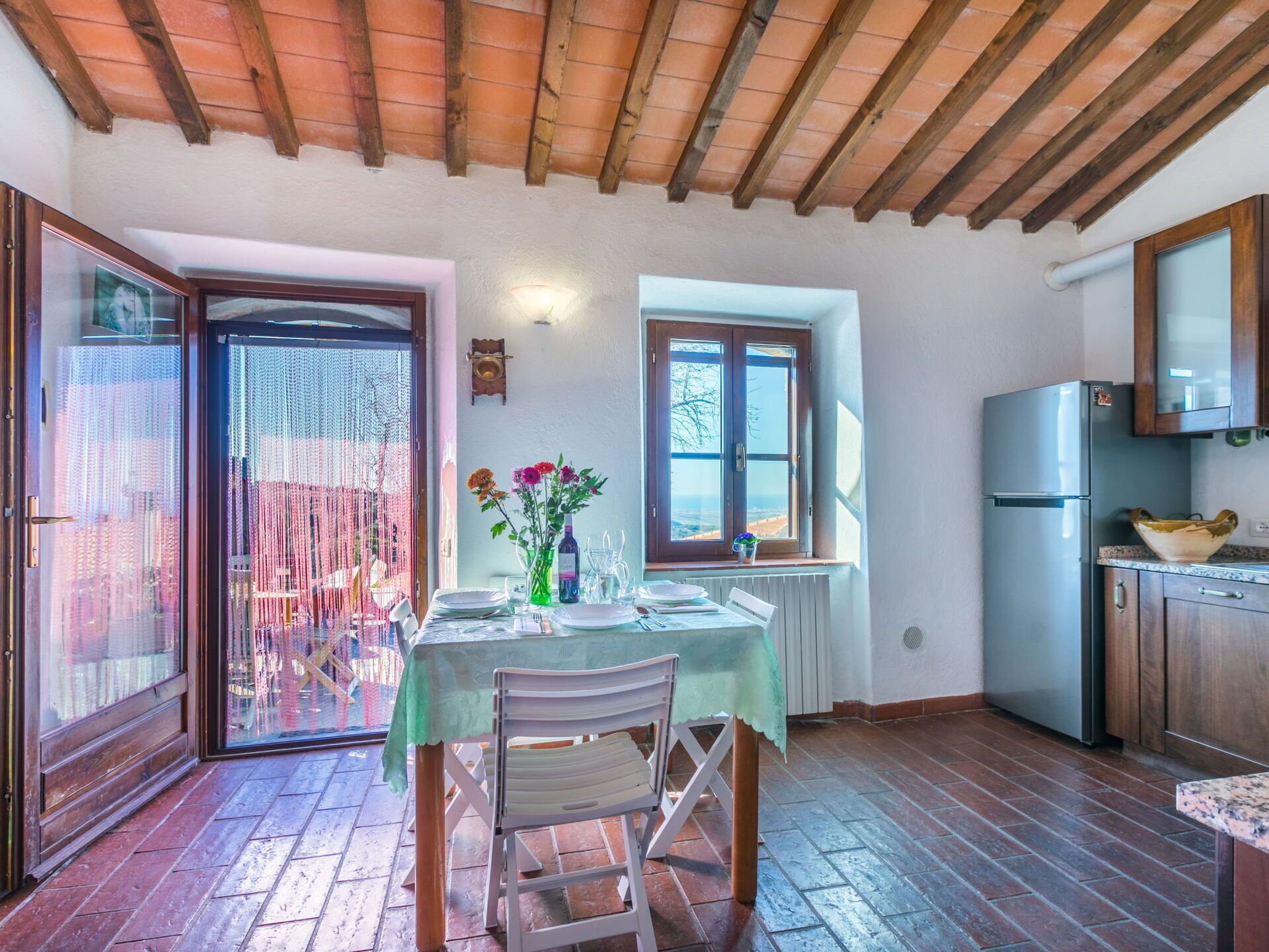 Angolo ristoro con tavolo apparecchiato per due, cucina con frigorifero e vista dalla finestra.