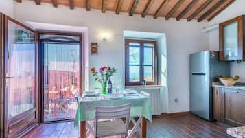 Angolo ristoro con tavolo apparecchiato per due, cucina con frigorifero e vista dalla finestra.