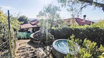 Een tuin met een hottub, houten trappen en een omheining.