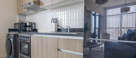 A modern kitchen with built-in appliances, a dining area with a sofa, and large windows.