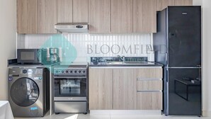 Een moderne keuken met houten kastjes, een zwarte koelkast, een wasmachine en een oven.