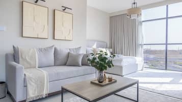 Un salon moderne avec un canapé, une table basse et une grande fenêtre donnant sur la ville.
