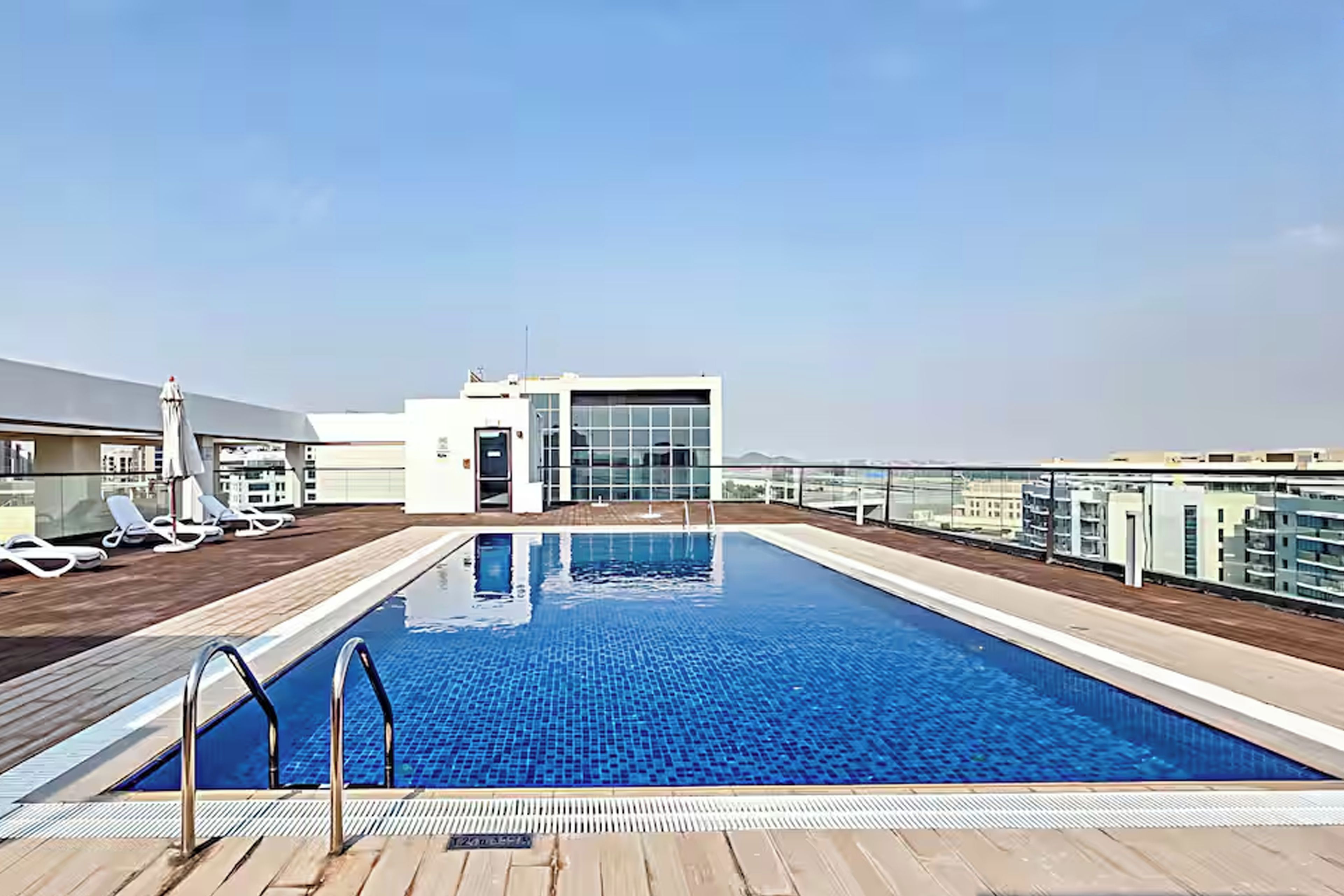 Une piscine sur le toit offrant une vue dégagée sur les gratte-ciel de la ville, des chaises longues et un bâtiment entièrement vitré.